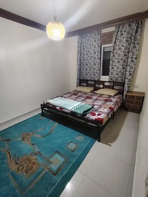 a bedroom with a bed and a blue rug at شقة مفروشة مدخل مستقل in Jurf ad Darāwīsh