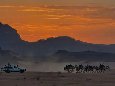 a group of people riding horses in the desert at sunset at Rum gate camp Fares in Disah