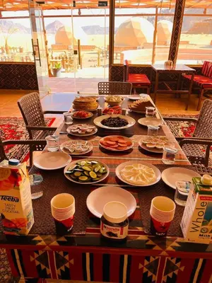 a table with plates of food and cups on it at Wadi Rum Quiet luxury camp in Wadi Rum