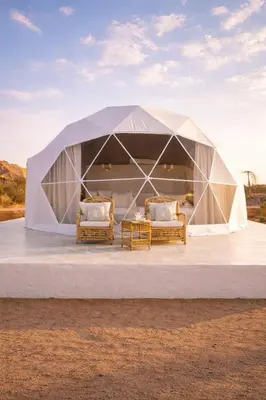 a tent with two chairs and a table on a stage at Wadi Rum Quiet luxury camp in Wadi Rum
