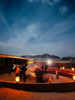 a group of people standing around a patio at night at Wadi Rum Quiet luxury camp in Wadi Rum