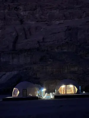 two domes in a field at night with lights at Wadi Rum Salman camp in Wadi Rum