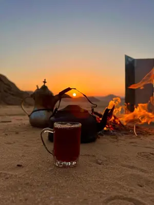 a cup of coffee sitting next to a camp fire at Wadi Rum Salman camp in Wadi Rum