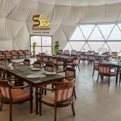 a restaurant with tables and chairs in a tent at Wadi Rum Salman camp in Wadi Rum