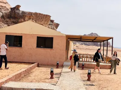 a group of people standing outside a building in the desert at Wadi Rum Salman camp in Wadi Rum