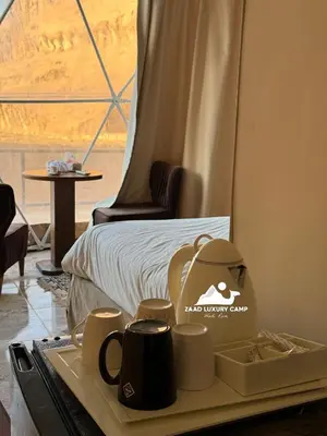 a tray with cups on a table in front of a bed at Wadi Rum ZAAD luxury Camp in Wadi Rum