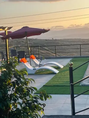 a couple of chairs and an umbrella on a roof at منتجع ومزرعة برجيل السد in Ballās