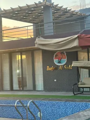 a building with a swimming pool in front of a building at منتجع ومزرعة برجيل السد in Ballās