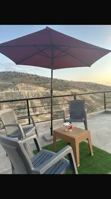 a patio with a table and an umbrella at منتجع ومزرعة برجيل السد in Ballās