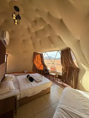 a bedroom with two beds and a large window at Wadi Rum Hala camp in Wadi Rum