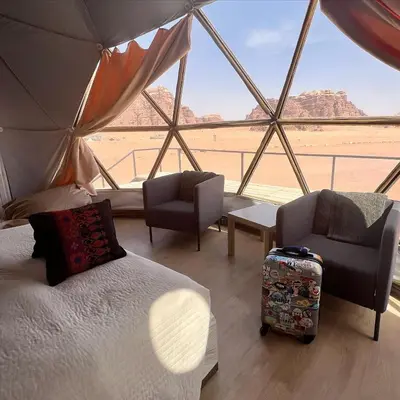 a room with a bed and chairs and a view of the desert at Wadi Rum Hala camp in Wadi Rum