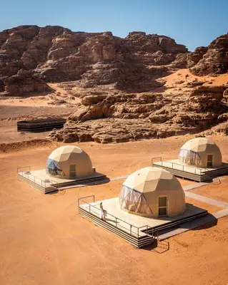 three tents in the desert with a mountain in the background at Wadi Rum Hala camp in Wadi Rum