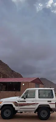 a white truck parked in front of a building at مخيم جمال الطبيعه in Wadi Rum