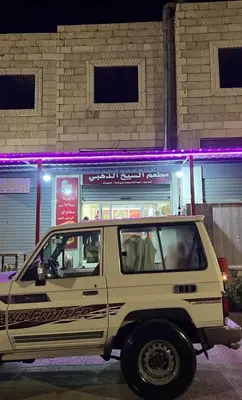 a white jeep parked in front of a store at مخيم جمال الطبيعه in Wadi Rum