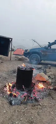 a camp fire in front of a car and a tent at Jordan trail from dana to petra in Dana
