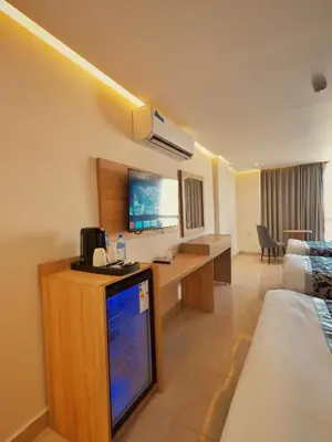 a hotel room with a tv and a desk in a room at Grand Season Hotel in Aqaba