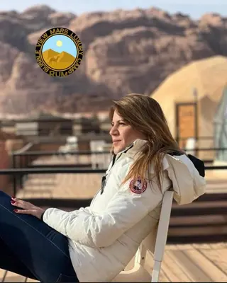 a woman sitting on a bench in front of a mountain at RUM BUBBLES VIEW MARS lUXURY CAMP in Wadi Rum