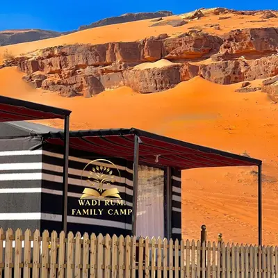 a building in the desert next to a sand hill at RUM FAMiLY BUBBLES &BEDOUIN CAMP in Wadi Rum