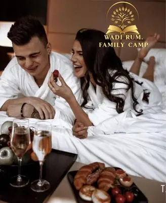 a man and a woman sitting in bed with a tray of food at RUM FAMiLY BUBBLES &BEDOUIN CAMP in Wadi Rum