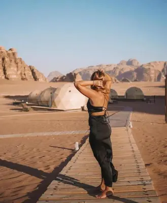 a woman standing on the beach talking on a cell phone at Rum plaza camp in Wadi Rum