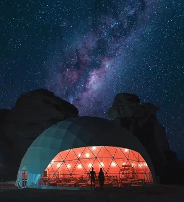 two people standing in front of a domed building at night at Rum plaza camp in Wadi Rum