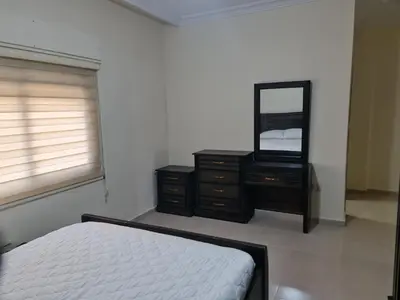 a bedroom with a bed and a dresser and a mirror at Samer Apartment in Amman