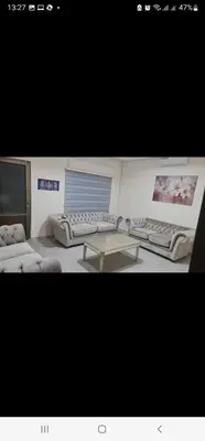 a living room with two beds and a table at Samer Apartment in Amman