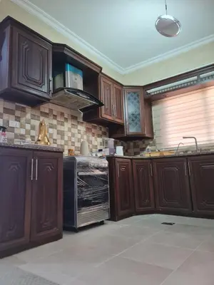 a kitchen with wooden cabinets and a black appliance at Samer Apartment in Amman