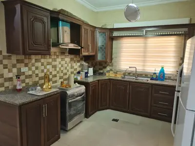 a kitchen with wooden cabinets and a sink at Samer Apartment in Amman