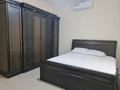 a bedroom with a bed and a wooden cabinet at Samer Apartment in Amman