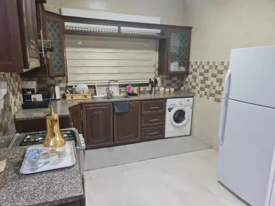 a kitchen with a white refrigerator and a dishwasher at Samer Apartment in Amman