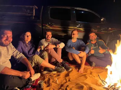 a group of people sitting around a fire at calm Rum in Wadi Rum