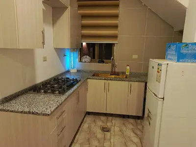 a kitchen with a stove and a white refrigerator at شاليه الاميرات in Sowayma