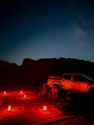 a truck parked in the desert at night with candles at Luxury Desert Camp in Disah