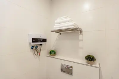 a white bathroom with a shelf with towels on it at Shamsi Apartments 223 in Amman