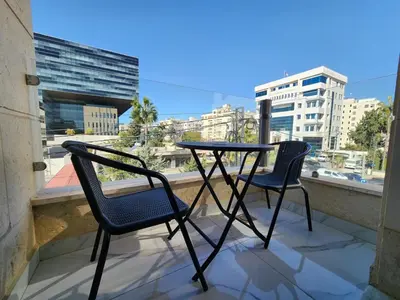 a table and two chairs on a balcony with a view at Shamsi Apartments 329 in Amman