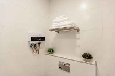 a white bathroom with white towels on a shelf at Shamsi Apartments 330 in Amman