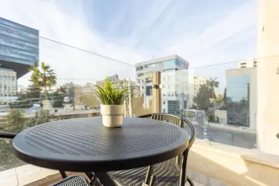 a black table with a potted plant on a balcony at Shamsi Apartments 436 in Amman