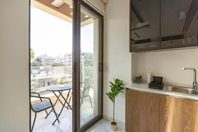 a kitchen with a window and a table with chairs at Shamsi Apartments 436 in Amman