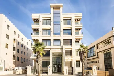 a white building with palm trees in front of it at Shamsi Apartments 437 in Amman