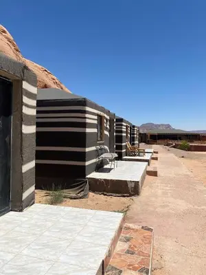 a row of buildings with benches in the desert at Crown Luxury Camp in Wadi Rum