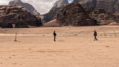 two people standing in a desert with mountains in the background at Crown Luxury Camp in Wadi Rum