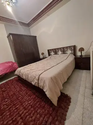 a bedroom with a large bed and a red rug at شقة مفروشة في البنيات - بالقرب من جامعة البتراء in Amman