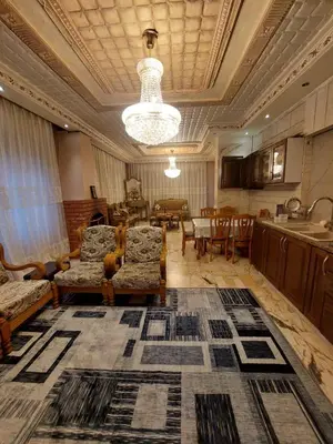 a living room with couches and a table and a kitchen at شقة مفروشة في البنيات - بالقرب من جامعة البتراء in Amman