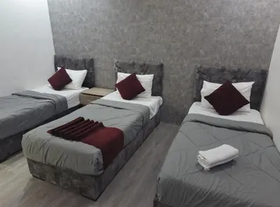 a room with three beds with red pillows at Gate Inn in Amman