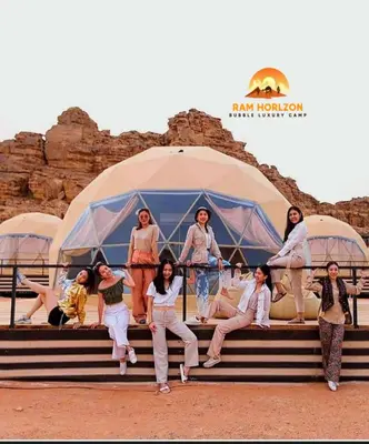 a group of people sitting on steps in front of a tent at RAM HORlZON LUXURY CAMP in Wadi Rum