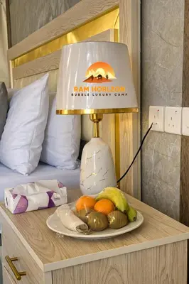 a lamp on a table with a plate of fruit at RAM HORlZON LUXURY CAMP in Wadi Rum