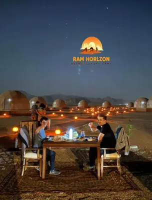 a group of people sitting at a table at night at RAM HORlZON LUXURY CAMP in Wadi Rum