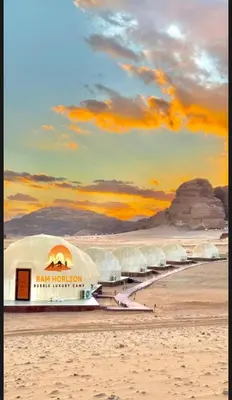 a group of domes on a beach with a sunset at RAM HORlZON LUXURY CAMP in Wadi Rum