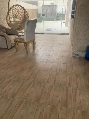 a room with a wooden floor with a chair and a couch at Amman Apartment 123 in Amman